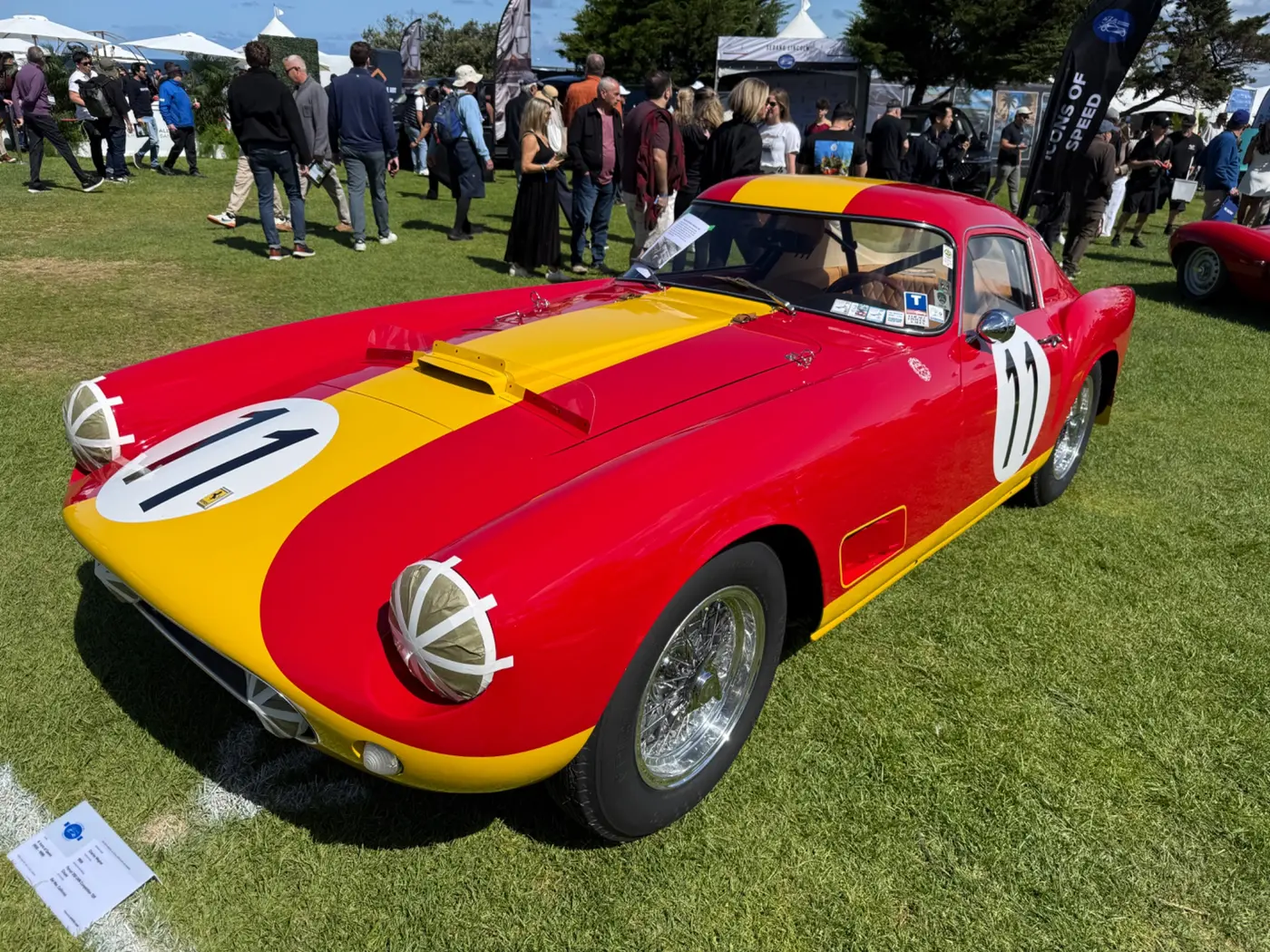 Historic red-and-yellow competition car on a concours lawn